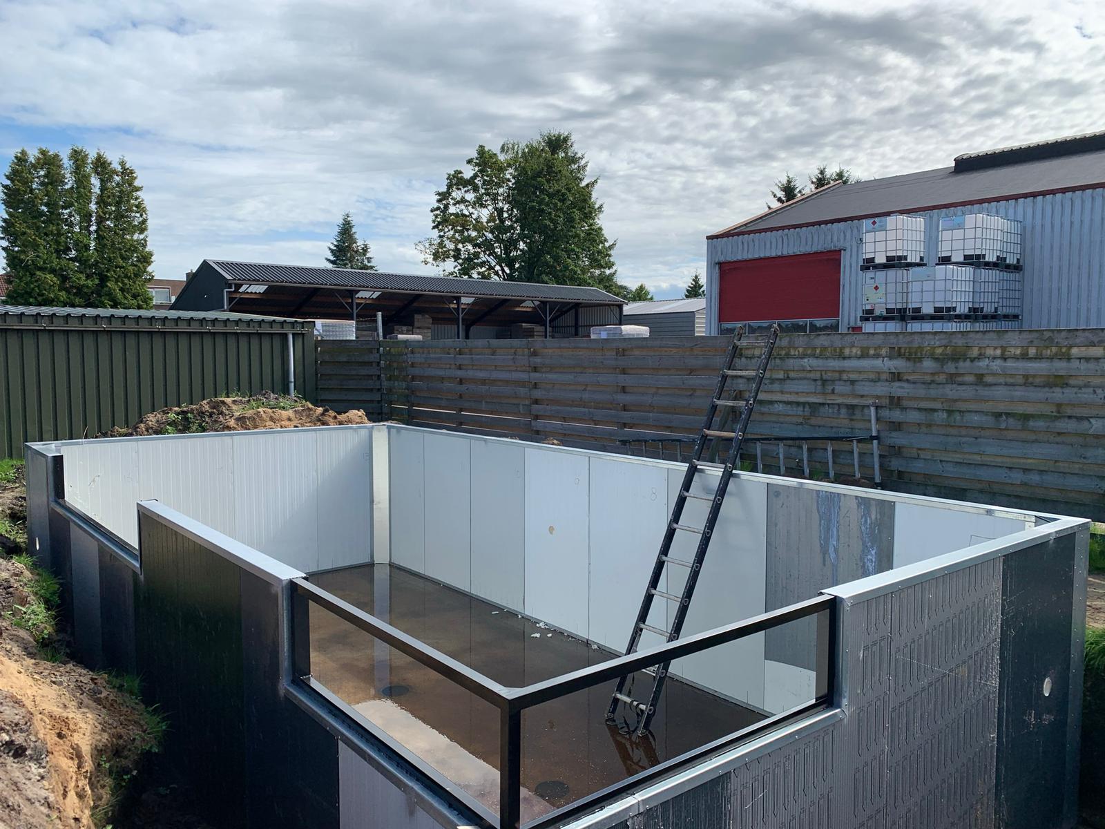 Stalen vijverframe en witte sandwichpanelen tijdens de bouw in Bovensmilde