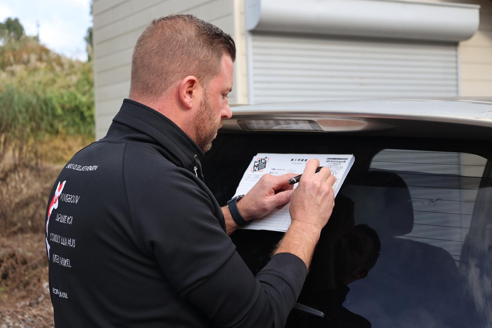 Arjan noteert gegevens op een koi-certificaat bij een auto
